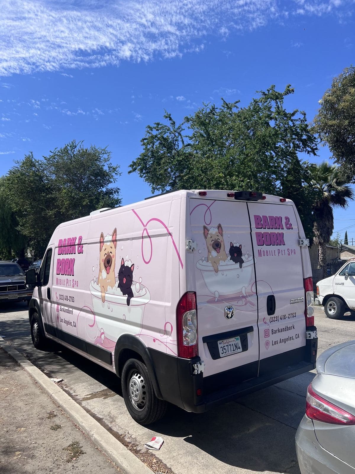 Rear three-quarter view of the Bark and Bork mobile grooming van showing the full brand wrap